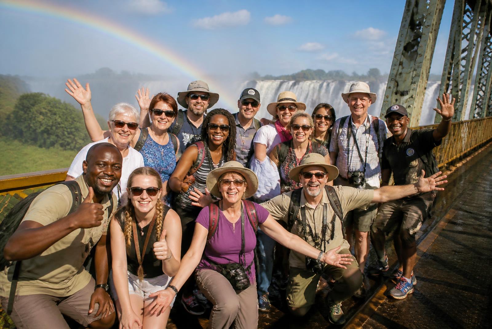 Happy tour group on the Victoria Falls bridge under a rainbow